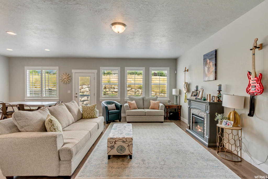 Hardwood floored living room with plenty of natural light, a fireplace, and a textured ceiling