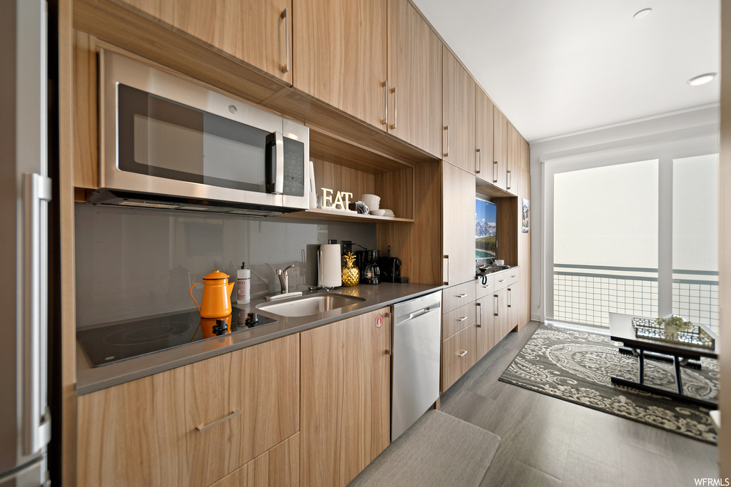 Kitchen featuring backsplash, dark countertops, wood-type flooring, and stainless steel appliances