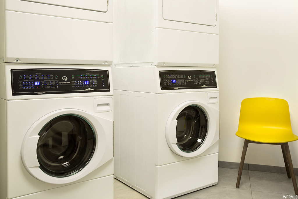 Laundry area with washer and clothes dryer, stacked washer / drying machine, and light tile flooring
