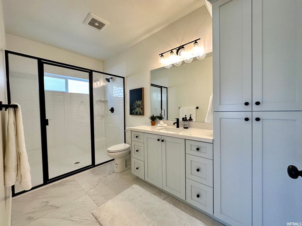 Bathroom featuring an enclosed shower, vanity, light tile flooring, and mirror