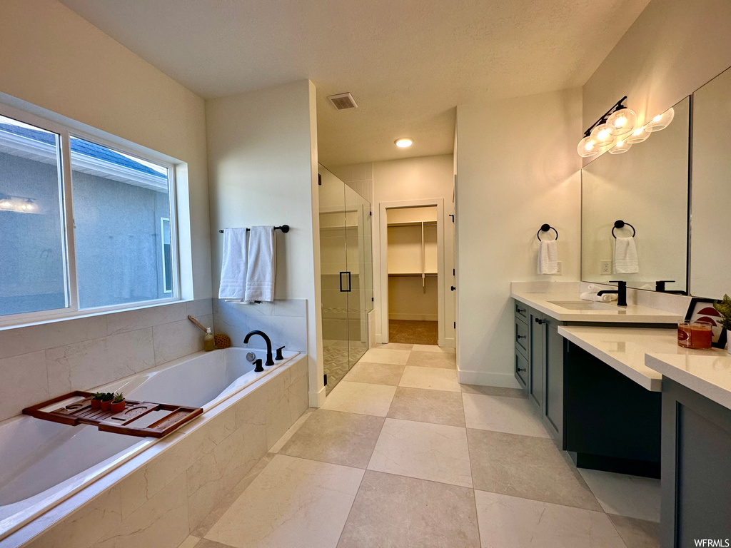 Bathroom with mirror, light tile flooring, large vanity, and independent shower and bath