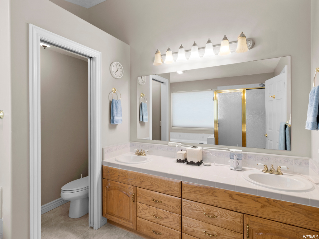 Bathroom featuring mirror, double large vanity, a bath, and light tile flooring