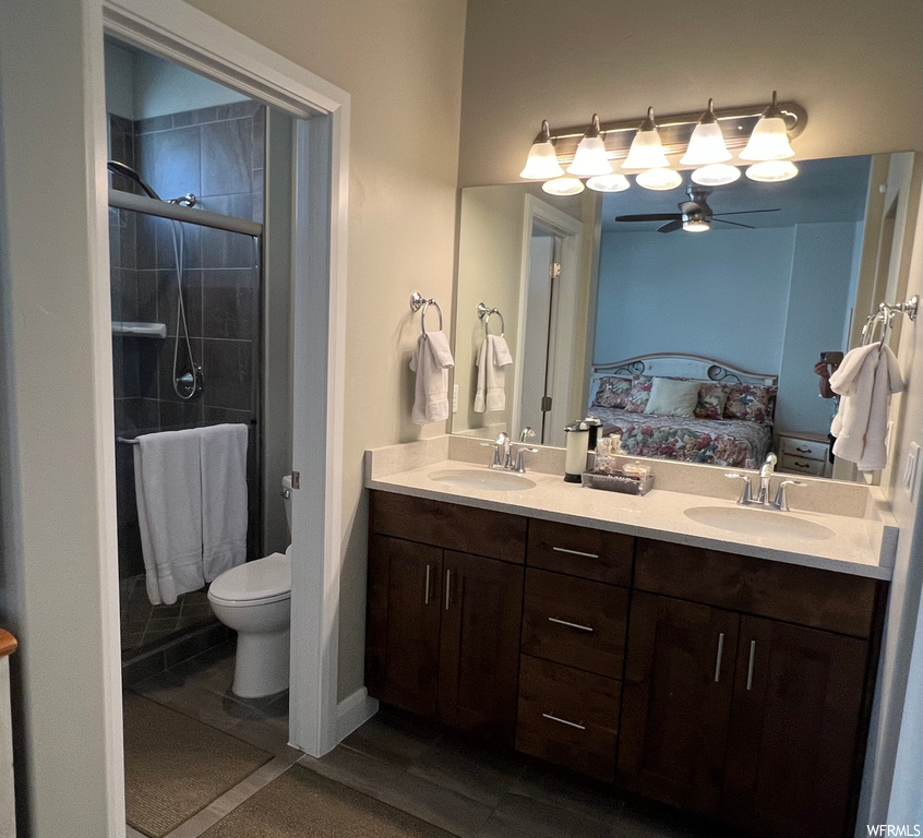 Bathroom with double vanity, a shower with shower door, mirror, and ceiling fan