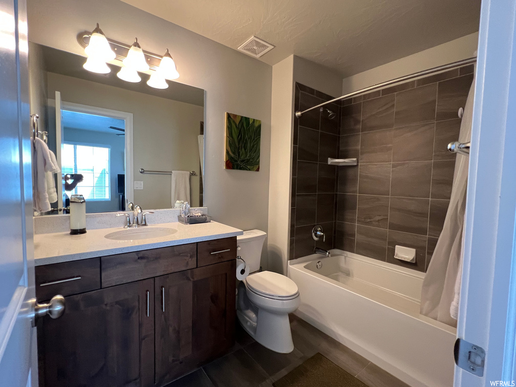 Full bathroom with shower / bath combo with shower curtain, dark tile flooring, mirror, and vanity