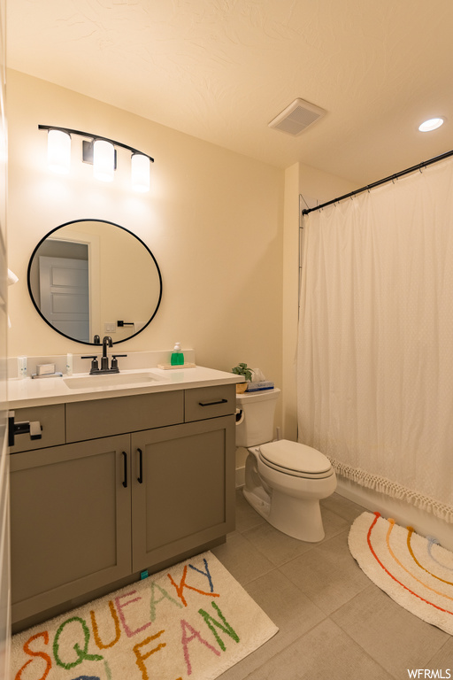 Bathroom with mirror, large vanity, and light tile floors