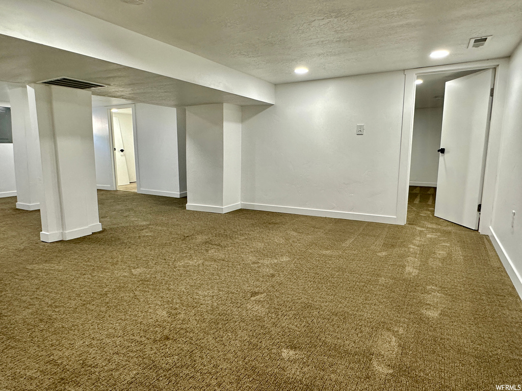 Basement featuring light carpet and a textured ceiling