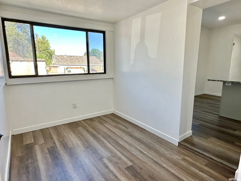 Empty room with a textured ceiling, a wealth of natural light, and light hardwood floors