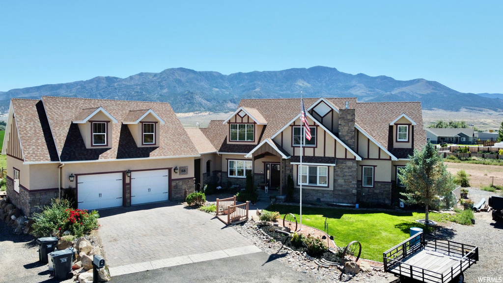 View of front of home featuring garage, a front yard, and a mountain view