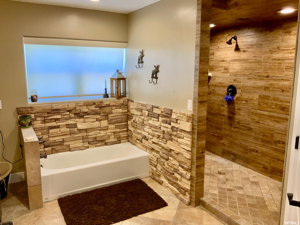 Bathroom featuring light tile flooring and shower with separate bathtub