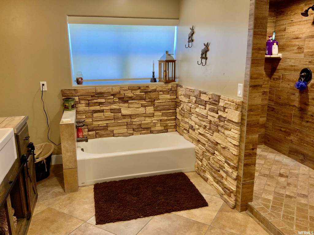 Bathroom featuring separate shower and tub, vanity, and light tile floors