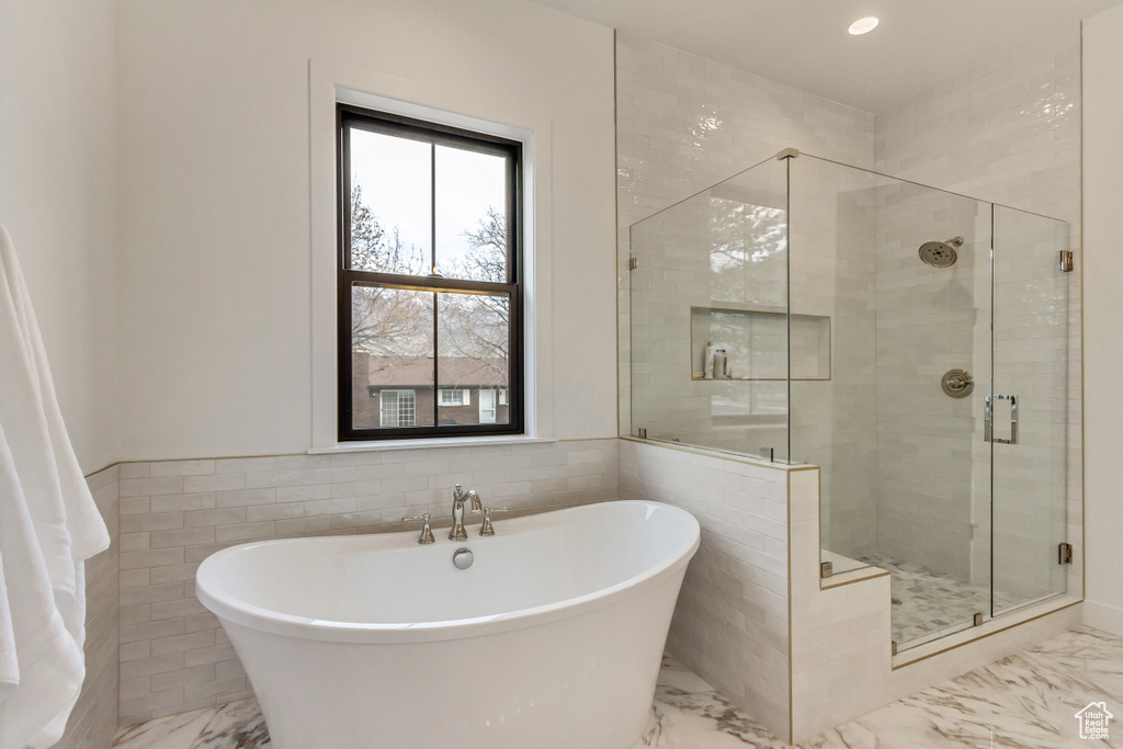 Bathroom featuring tile walls, tile flooring, plus walk in shower, and plenty of natural light