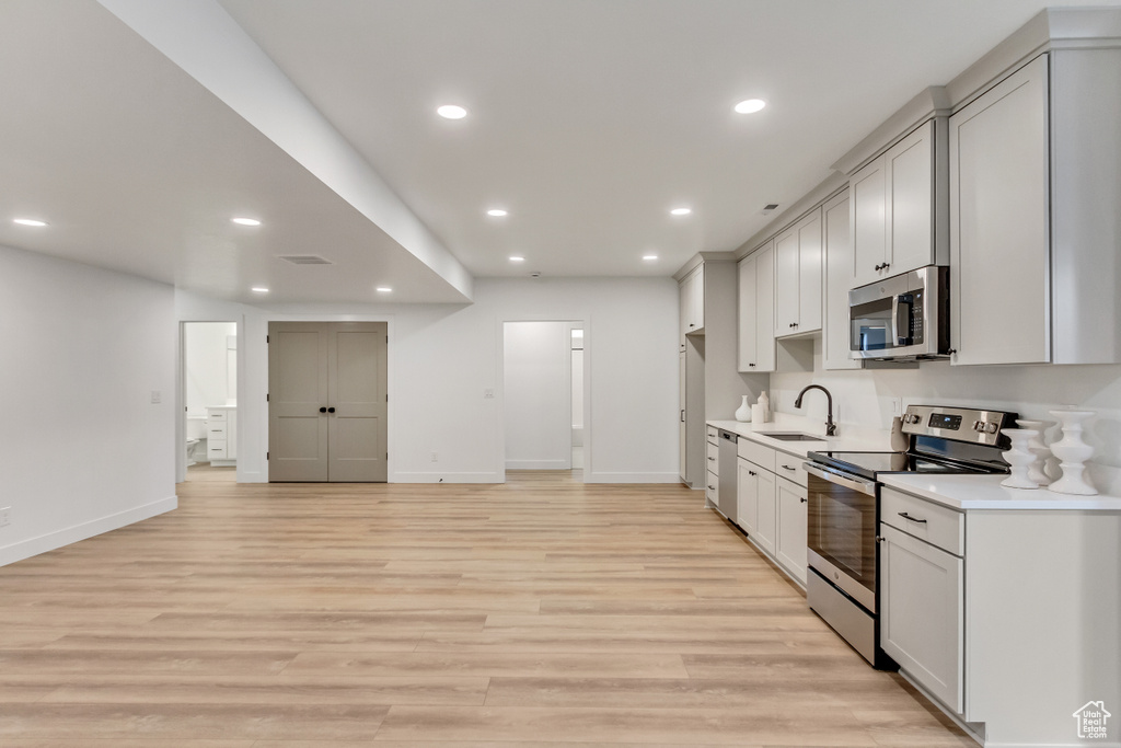 Kitchen with appliances with stainless steel finishes, light wood-type flooring, and sink