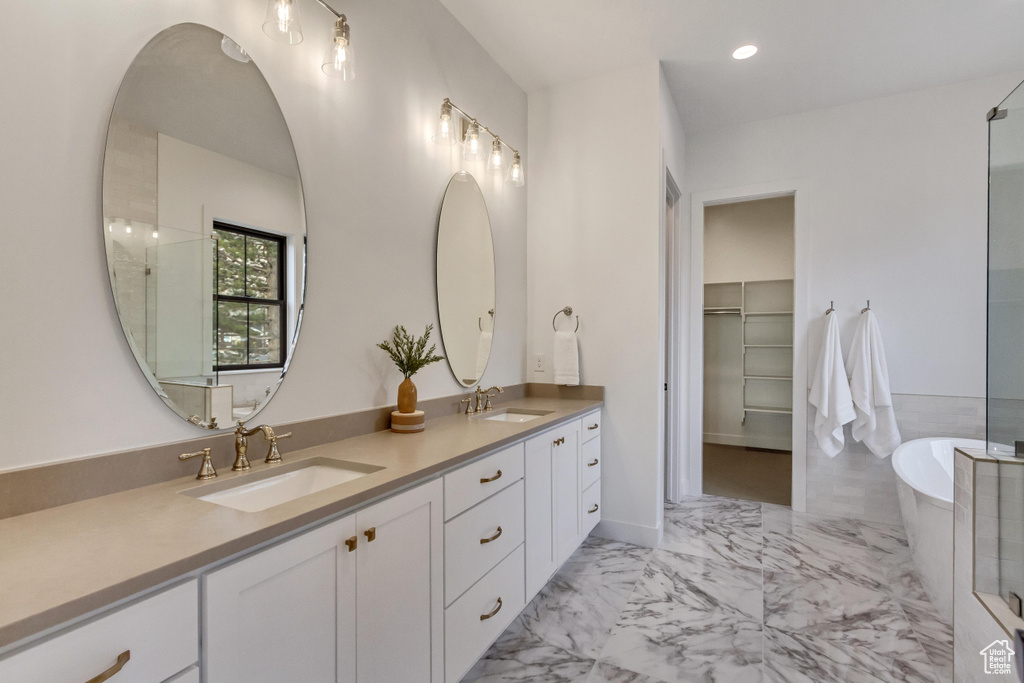 Bathroom featuring dual vanity, a bathtub, and tile floors