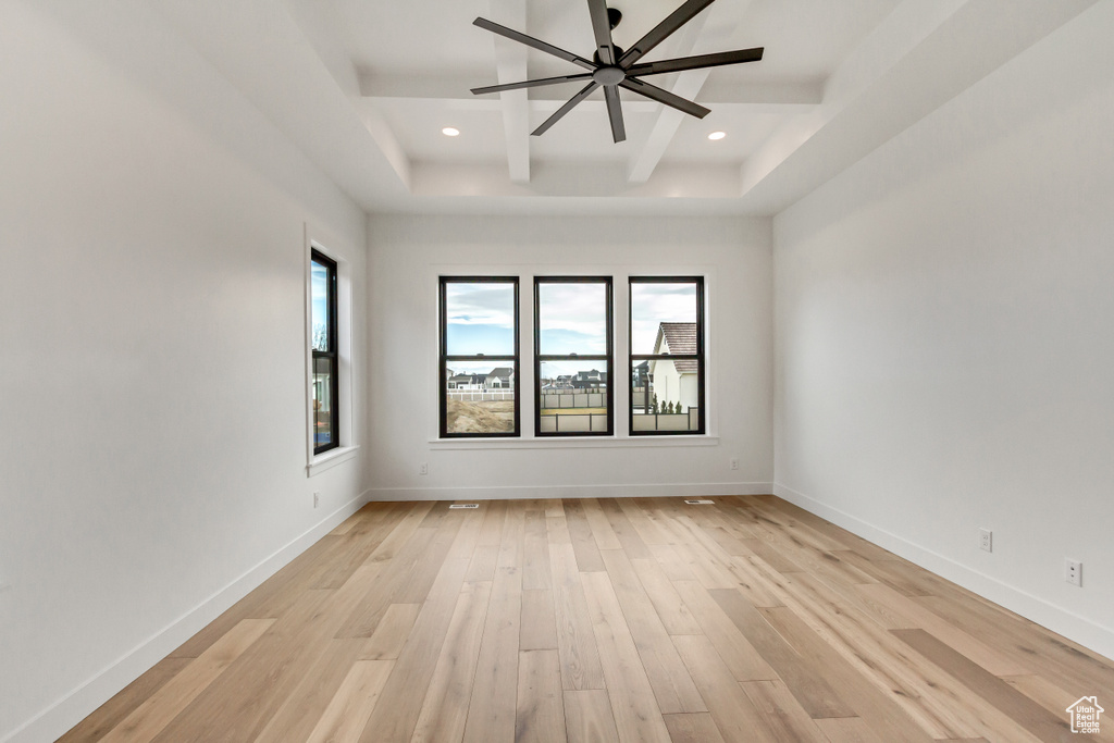 Unfurnished room featuring a raised ceiling, light hardwood / wood-style floors, and ceiling fan