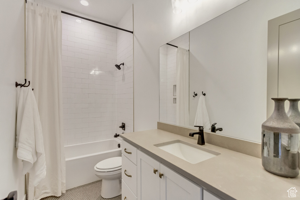 Full bathroom with shower / bath combo, vanity with extensive cabinet space, tile floors, and toilet