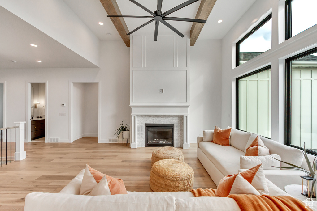 Living room with a towering ceiling, light hardwood / wood-style floors, and beam ceiling