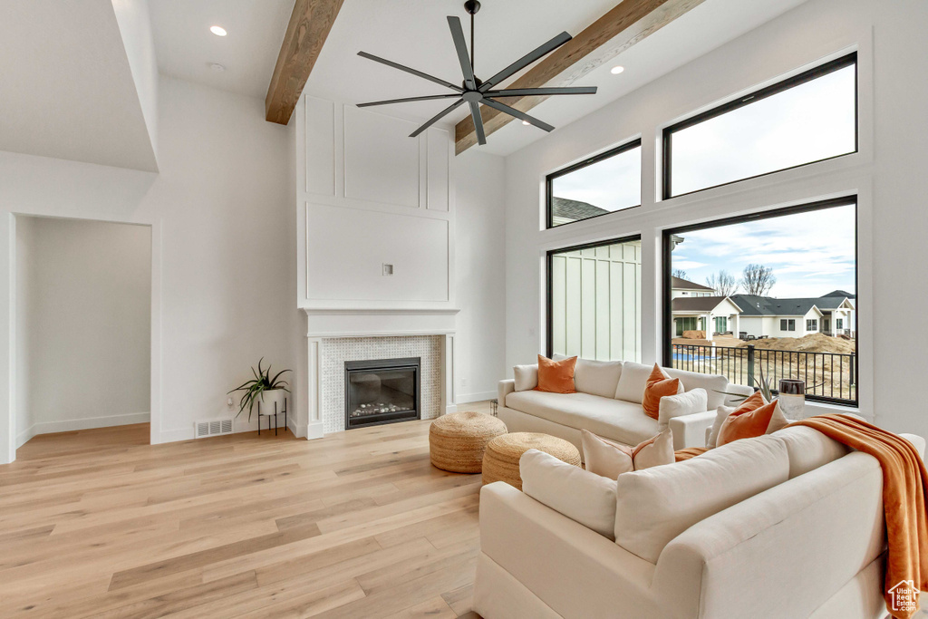 Living room featuring a towering ceiling, ceiling fan, light hardwood / wood-style flooring, and beamed ceiling