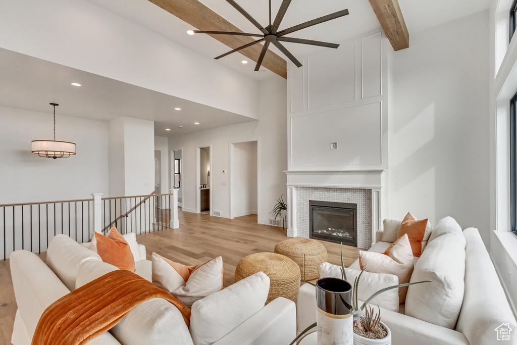 Living room featuring light hardwood / wood-style flooring, beam ceiling, a towering ceiling, and ceiling fan
