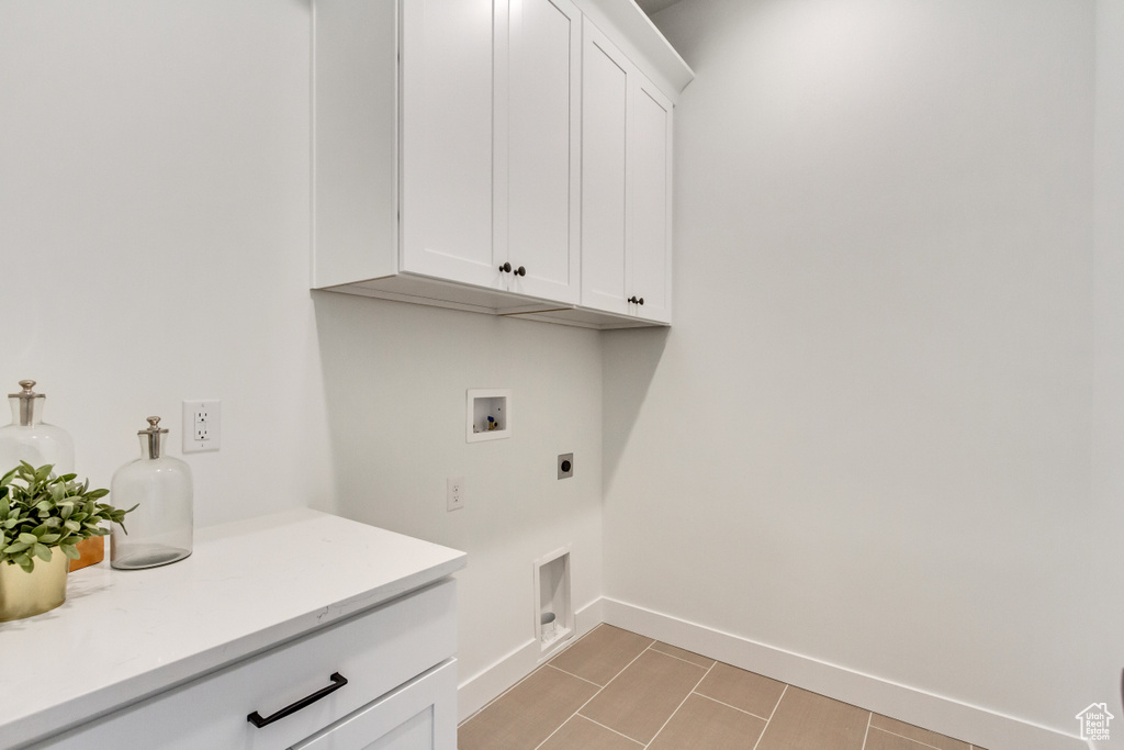 Laundry area with electric dryer hookup, light tile floors, hookup for a washing machine, and cabinets