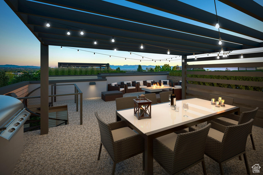Patio terrace at dusk featuring area for grilling and an outdoor living space with a fire pit