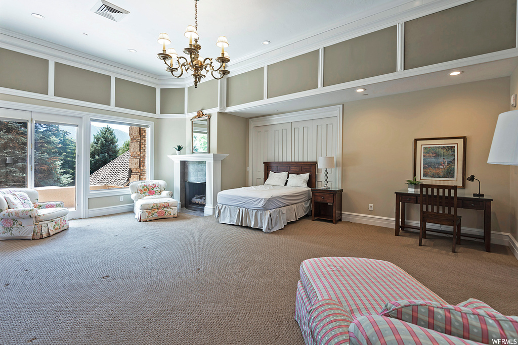 Bedroom with a notable chandelier, light carpet, crown molding, a fireplace, and a high ceiling