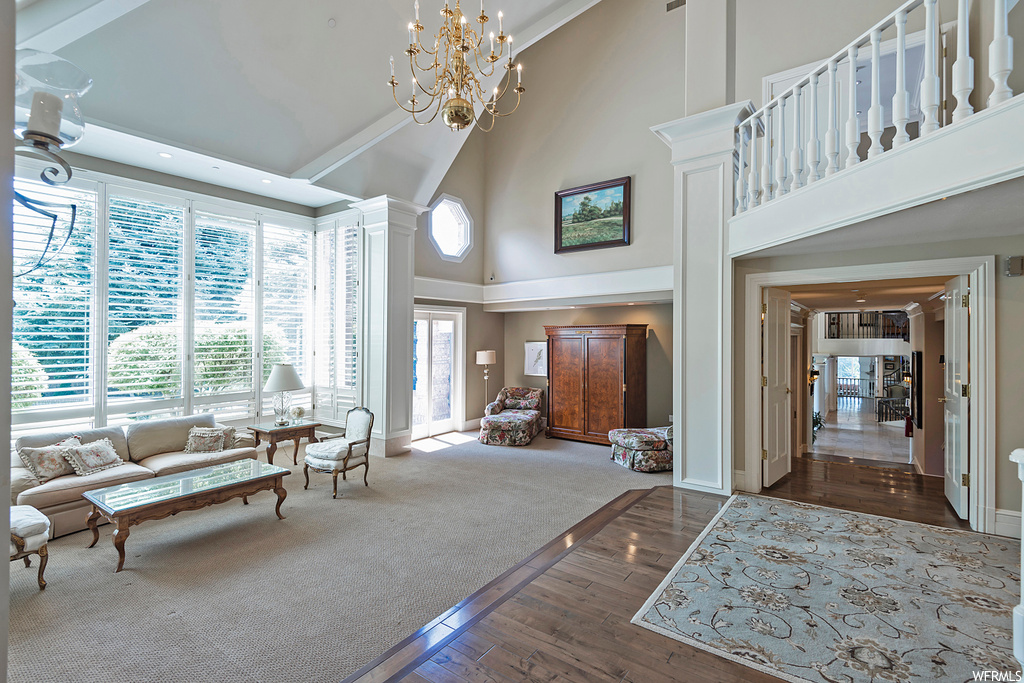 Foyer featuring a high ceiling, a notable chandelier, carpet floors, and lofted ceiling