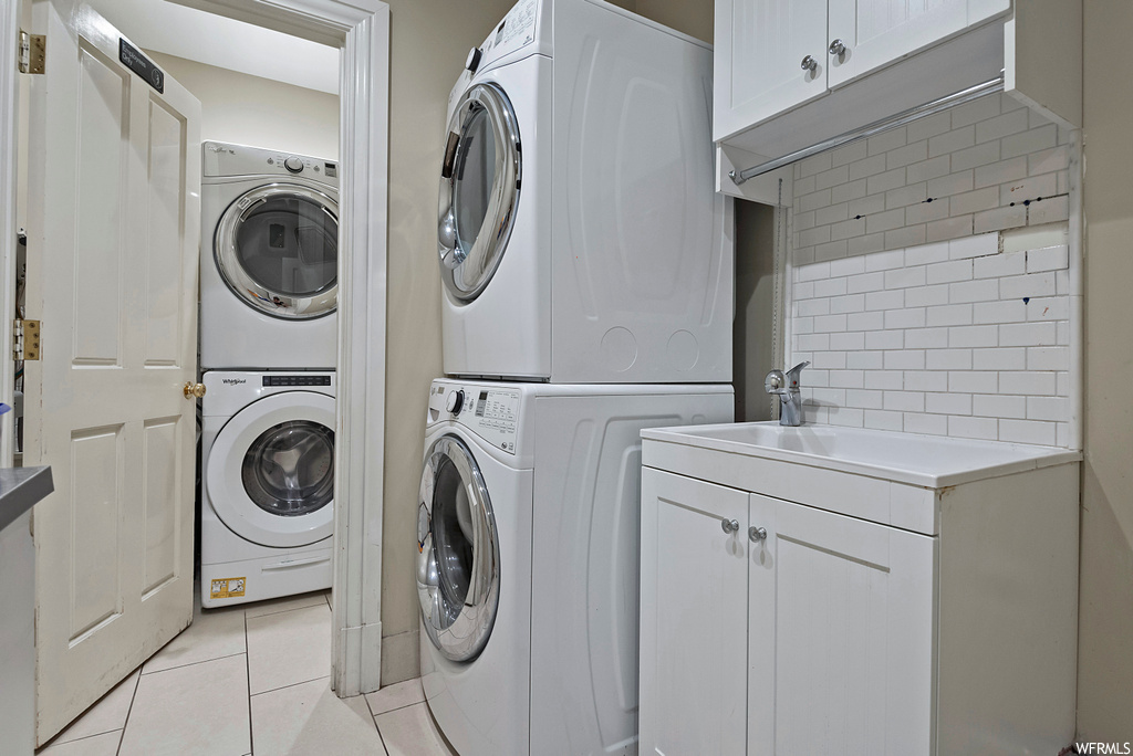 Laundry room featuring stacked washer and clothes dryer and light tile floors