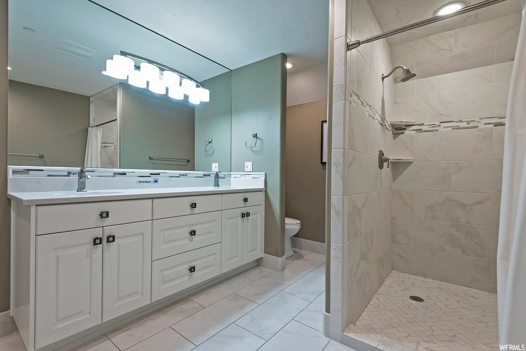 Bathroom with dual large vanity, light tile flooring, mirror, and a shower with curtain