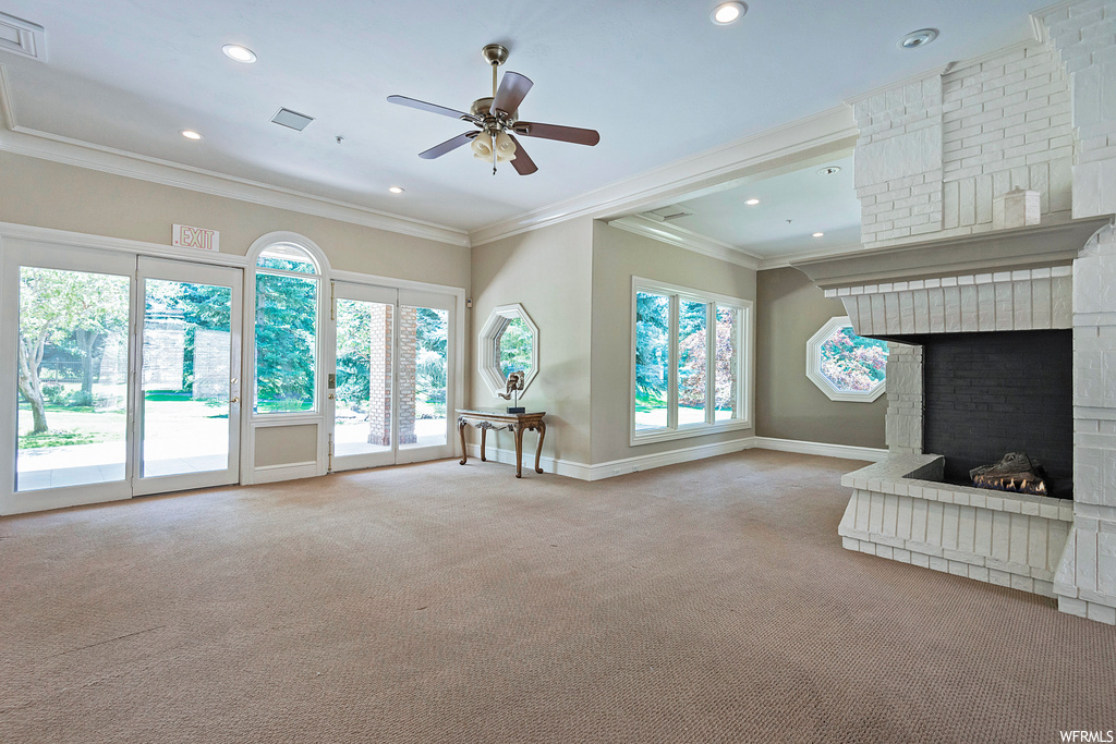 Living room featuring light carpet, a healthy amount of sunlight, ceiling fan, crown molding, and a fireplace
