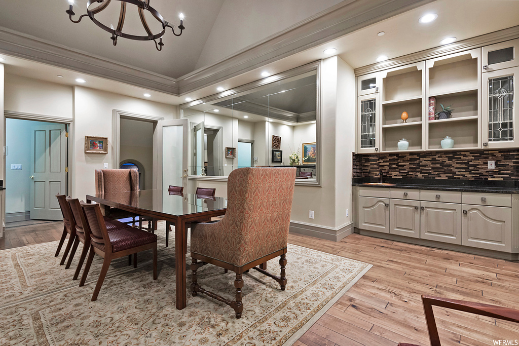 Dining room with crown molding, lofted ceiling, and light hardwood flooring