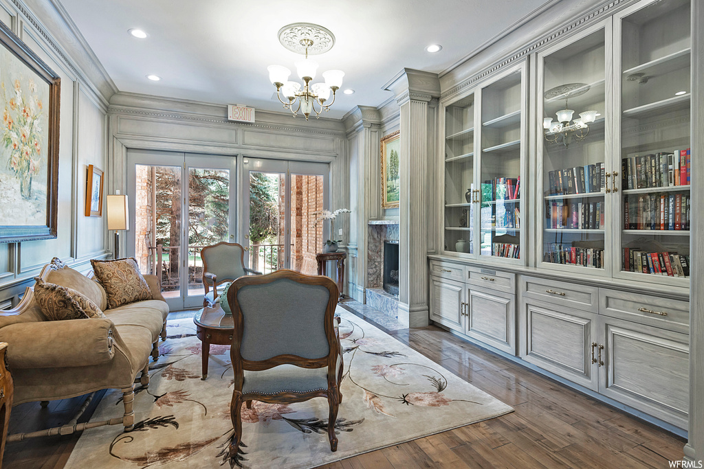Hardwood floored living room featuring a chandelier, ornamental molding, and built in shelves