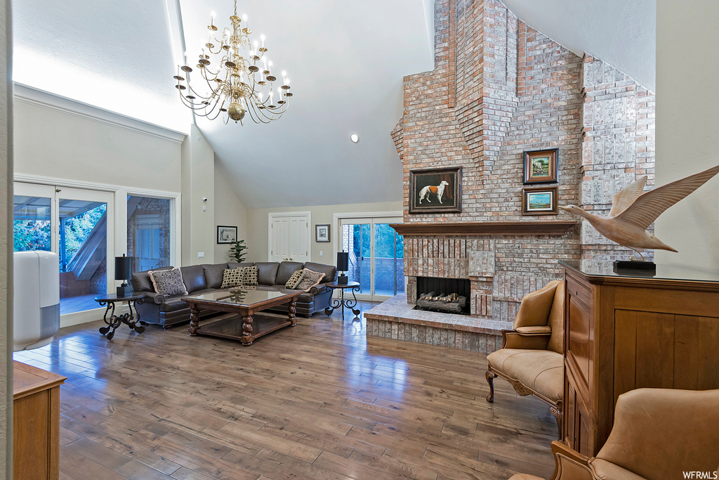 Living room with brick wall, light hardwood flooring, lofted ceiling, a fireplace, and a high ceiling