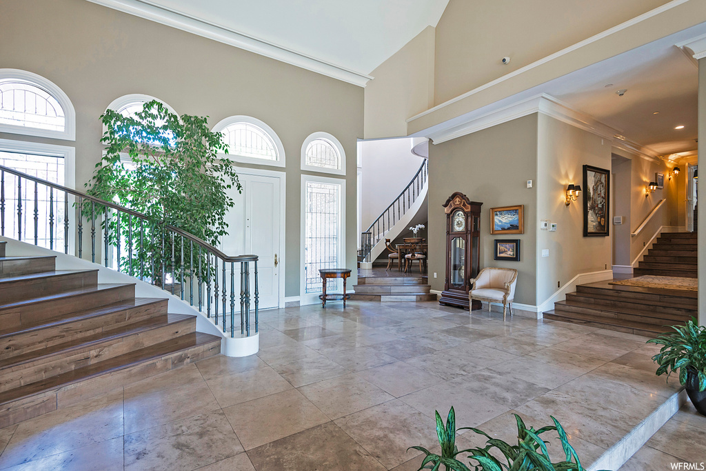 Foyer featuring ornamental molding, a high ceiling, and light tile flooring