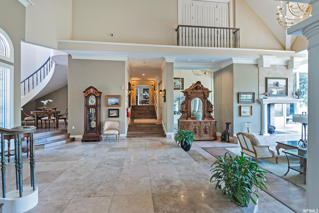 Entryway featuring a notable chandelier, a high ceiling, crown molding, and light tile flooring