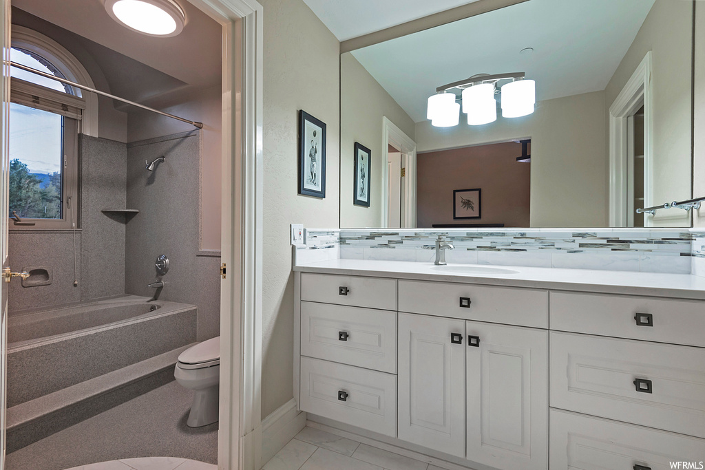 Full bathroom with vanity, light tile flooring, mirror, bathing tub / shower combination, and backsplash