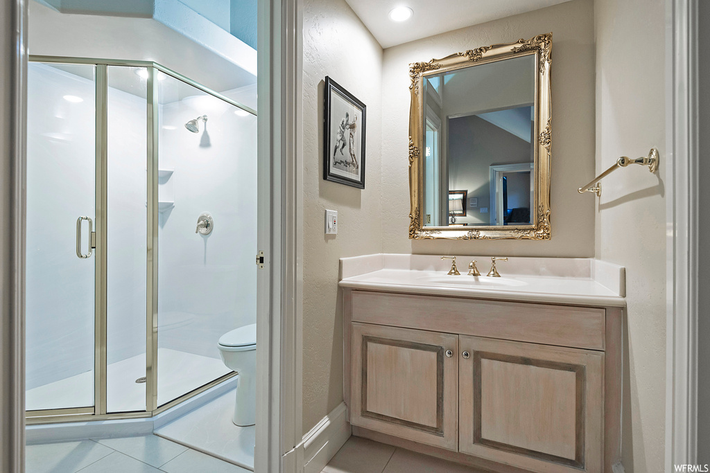 Bathroom with large vanity, light tile floors, mirror, and a shower with door