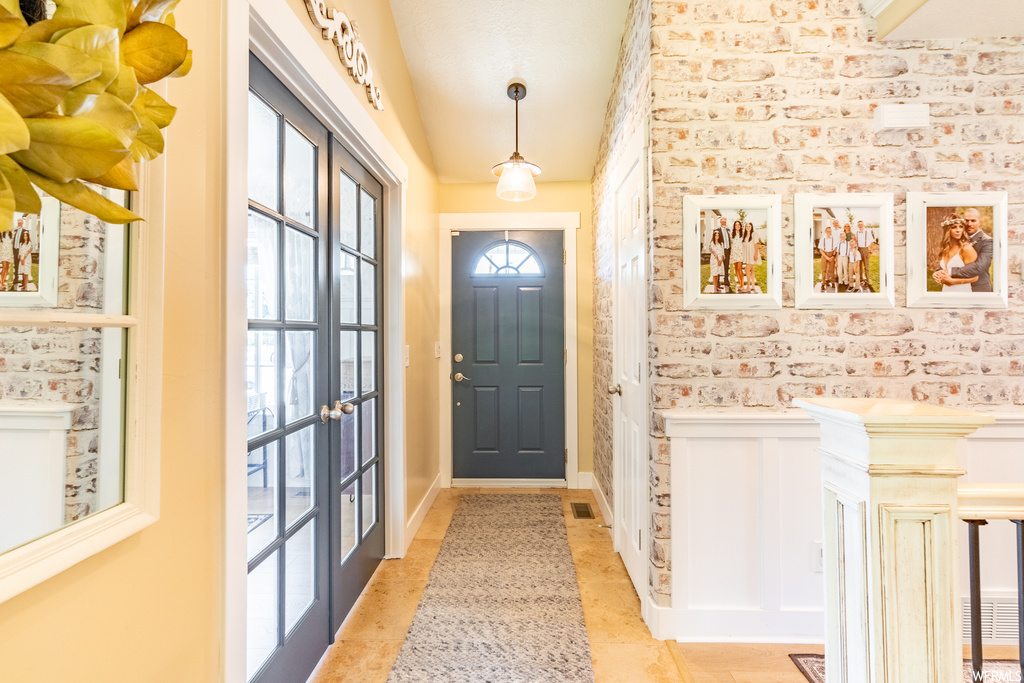 Tiled entrance foyer with a wealth of natural light and brick wall