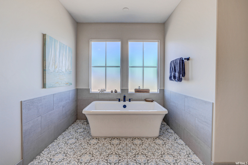 Bathroom with tile walls, a washtub, and light tile floors