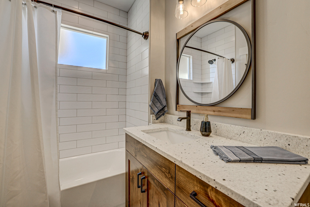 Bathroom featuring vanity with extensive cabinet space, shower / tub combo with curtain, and mirror