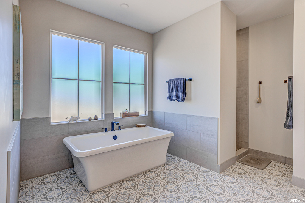 Bathroom featuring tile walls, independent shower and bath, and light tile floors