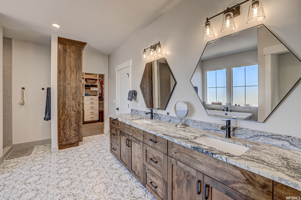 Bathroom featuring dual bowl vanity, mirror, and light tile floors