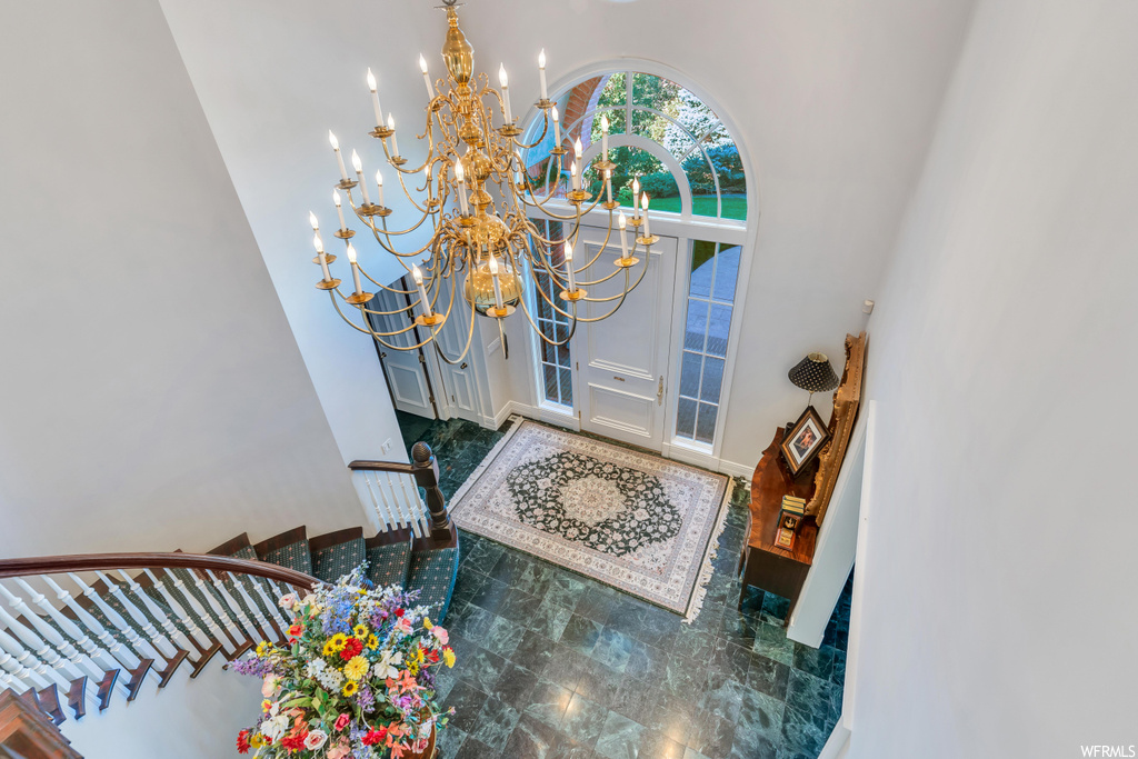 Tiled foyer entrance with a chandelier and a high ceiling
