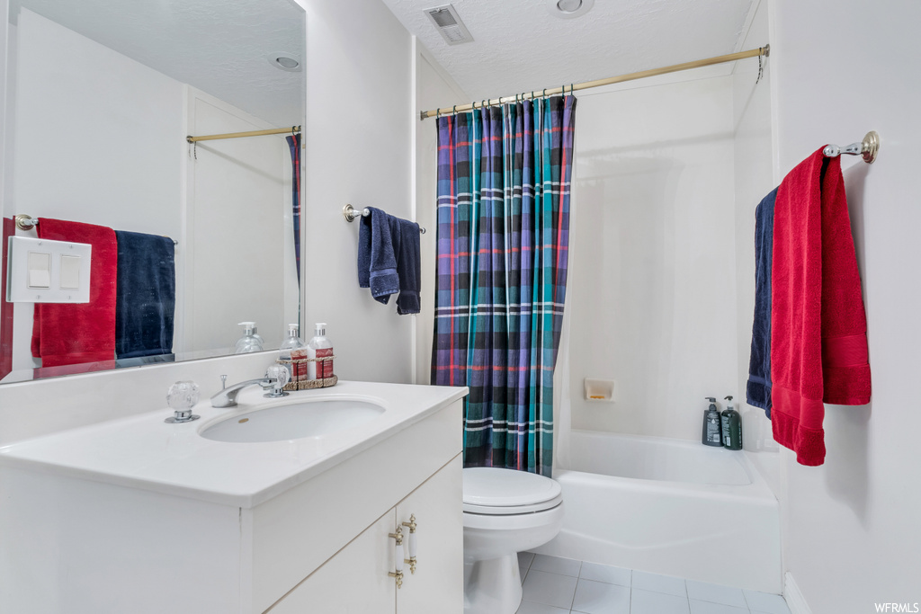 Full bathroom with a textured ceiling, mirror, light tile floors, oversized vanity, and shower / tub combo with curtain