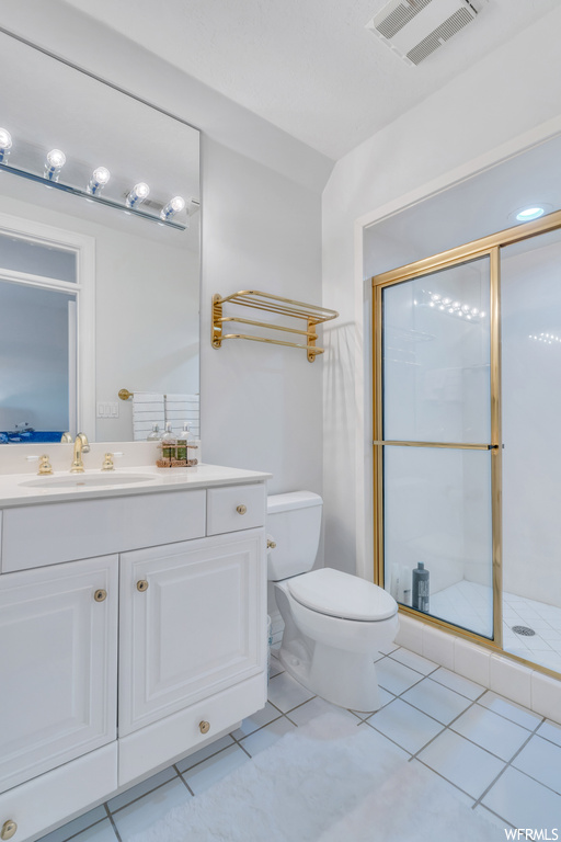 Bathroom with vanity, a shower with shower door, mirror, and light tile floors