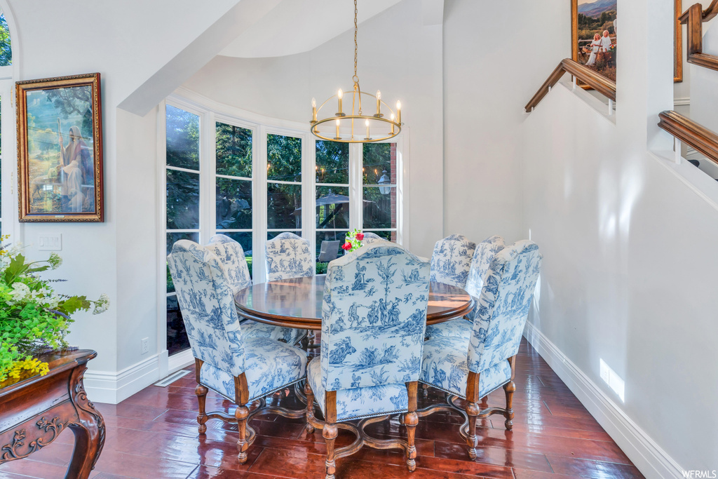 Hardwood floored dining room with a notable chandelier and vaulted ceiling