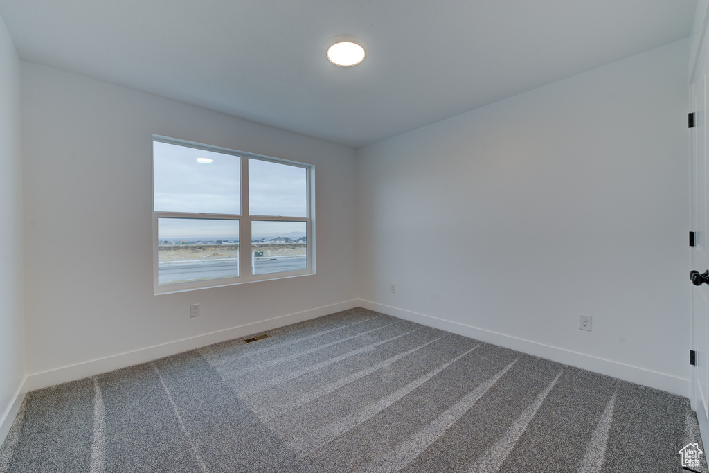 Empty room featuring a water view and dark colored carpet