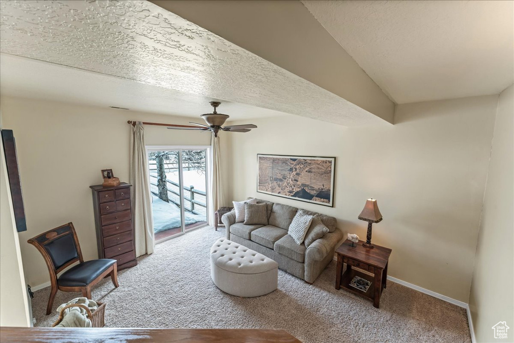 Carpeted living room with a textured ceiling and ceiling fan