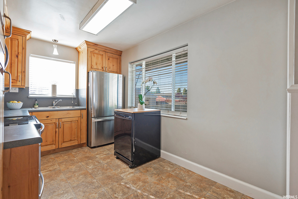 Kitchen with light tile flooring, brown cabinets, range, and stainless steel refrigerator