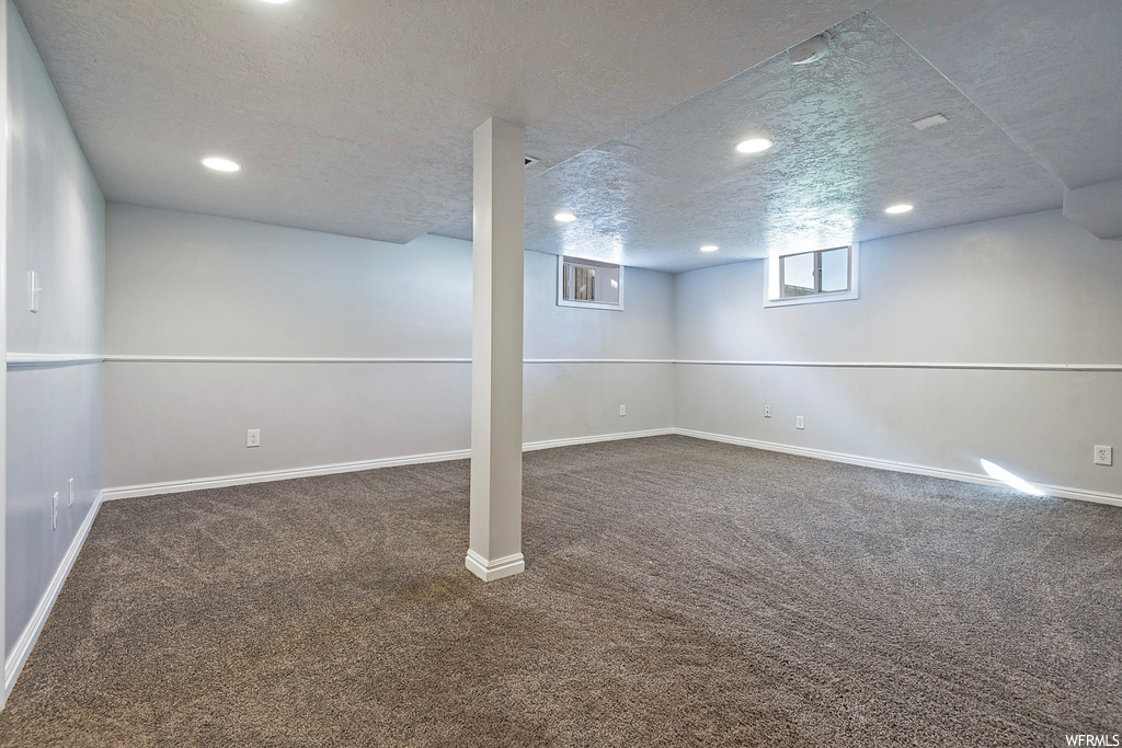 Basement featuring light carpet and a textured ceiling
