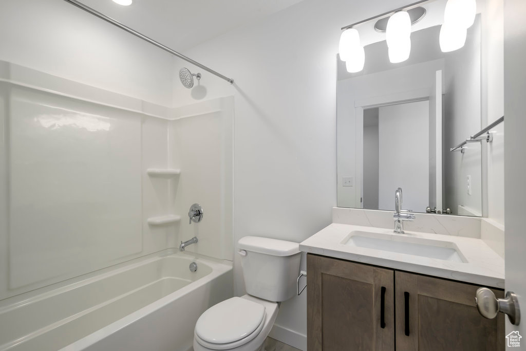 Full bathroom with toilet, large vanity, and tub / shower combination